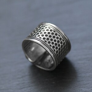 Puede incluir: Un anillo de plata con un dise&ntilde;o texturizado y estampado. El anillo tiene una banda ancha con un patr&oacute;n repetitivo de peque&ntilde;os c&iacute;rculos.