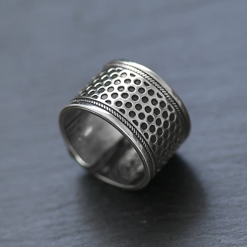 Puede incluir: Un anillo de plata con un dise&ntilde;o texturizado y estampado. El anillo tiene una banda ancha con un patr&oacute;n repetitivo de peque&ntilde;os c&iacute;rculos.