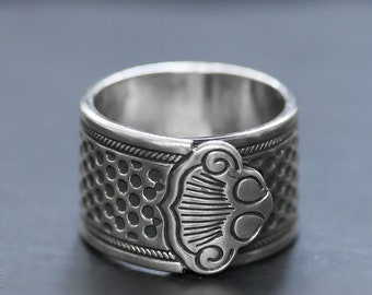 Könnte beinhalten: Ein silberner Ring mit einem strukturierten Design und einem dekorativen Detail an der Seite.