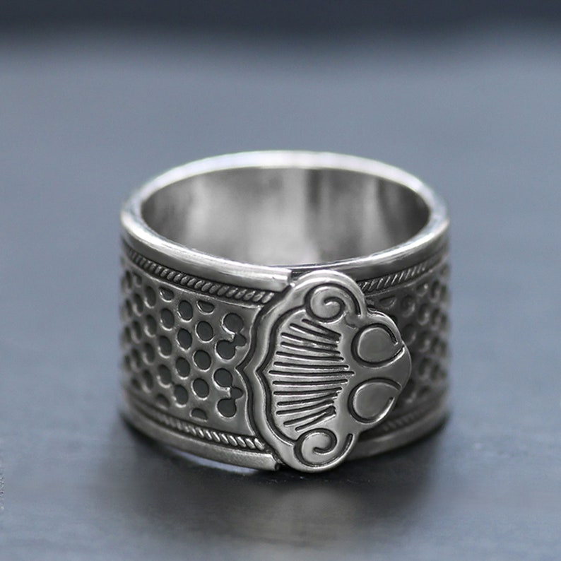Puede incluir: Un anillo de plata con un dise&ntilde;o texturizado y un detalle decorativo en el lateral.