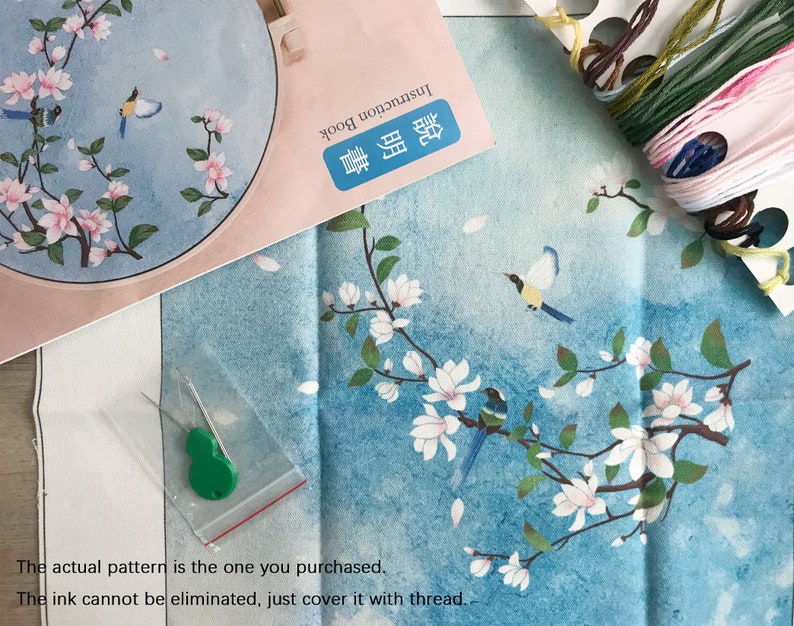 May include: A close-up of a needlepoint embroidery kit featuring a blue and white floral design with birds. The kit includes a pre-printed canvas, embroidery floss, needles, and instructions. The actual pattern is the one you purchased. The ink cannot be eliminated, just cover it with thread.