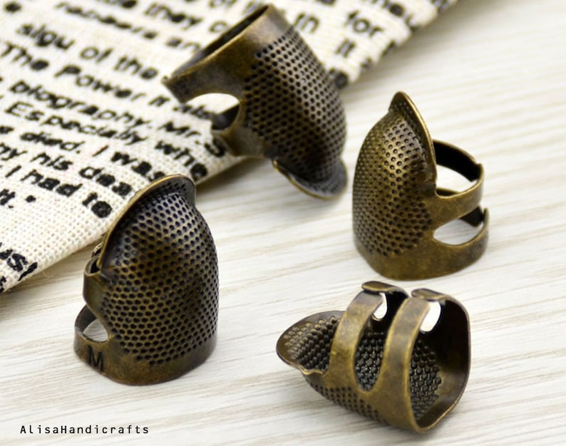 May include: Four antique gold-toned thimbles for sewing. The thimbles have a textured surface and are designed to fit on the finger.