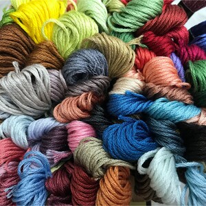 May include: A collection of colorful embroidery floss spools in various shades of blue, green, red, brown, pink, and yellow.