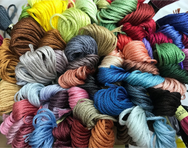 May include: A collection of colorful embroidery floss spools in various shades of blue, green, red, brown, pink, and yellow.