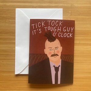 May include: A greeting card featuring a cartoon illustration of a man with a mohawk and a moustache. The text on the card reads "Tick Tock It's Tough Guy O'Clock".