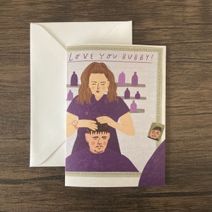 May include: Greeting card with a white envelope. The card features an illustration of a person getting their hair styled by a stylist. The text "Love You Bubby!" is at the top of the card.