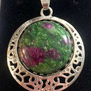 May include: A silver pendant necklace with a green and pink gemstone set in a filigree design.