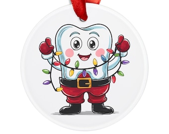 May include: A white ceramic Christmas ornament featuring a cartoon tooth character. The tooth is wearing a Santa-style outfit with a black belt and red pants and gloves. It is holding a string of colorful Christmas lights and has a red ribbon for hanging.