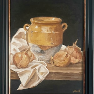 Puede incluir: Una pintura de bodegón de una olla de cerámica amarilla con un esmalte blanco, rodeada de cebollas sobre una mesa de madera con un paño blanco. La pintura está enmarcada en negro.