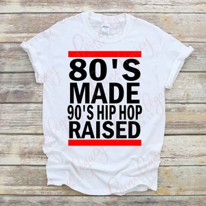 May include: White t-shirt with black text that reads "80's Made 90's Hip Hop Raised" with a red stripe above and below the text.