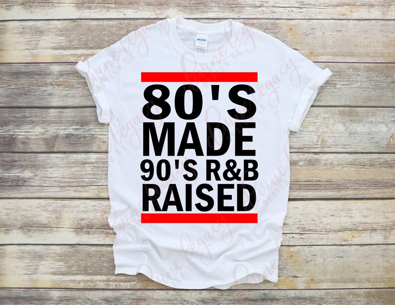 May include: White t-shirt with black text that reads "80's Made 90's R&B Raised" with a red bar above and below the text.