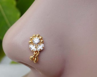 May include: Gold nose ring with a dangling chain and three clear stones.