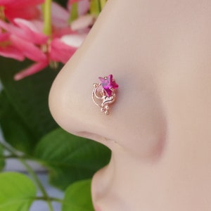 May include: A pink star-shaped gemstone nose ring with a gold-toned filigree design.