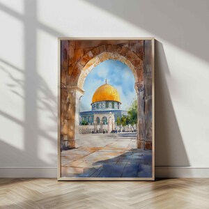 May include: Watercolor painting of the Dome of the Rock in Jerusalem, viewed through an archway. The artwork features a golden dome, blue sky, and detailed architectural elements. The painting is framed in a light wood frame.