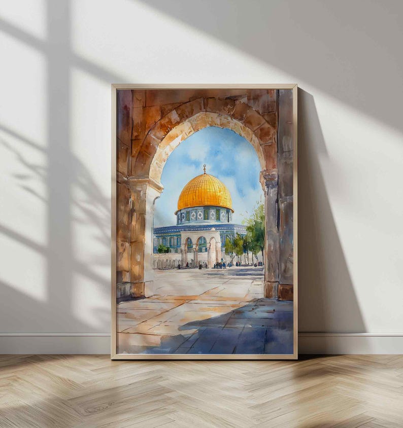 May include: Watercolor painting of the Dome of the Rock in Jerusalem, viewed through an archway. The artwork features a golden dome, blue sky, and detailed architectural elements. The painting is framed in a light wood frame.