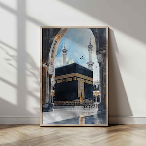 May include: Watercolor painting of the Kaaba in Mecca, framed in a light wood. The black cube-shaped structure is adorned with gold calligraphy. Two minarets rise in the background against a blue sky, with birds in flight.
