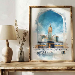 May include: A watercolor painting of the Kaaba in Mecca, Saudi Arabia. The painting features a clock tower and a mosque with a golden dome. The painting is framed in a wooden frame.