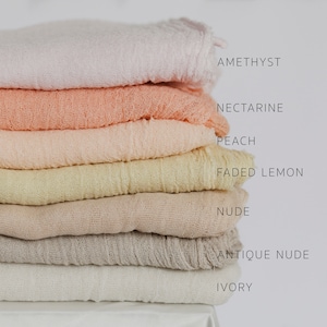 Puede incluir: Una pila de siete telas suaves y texturizadas en varios colores pastel. Los colores incluyen amatista, nectarina, melocotón, limón descolorido, nude, nude antiguo e marfil. Los nombres de los colores están impresos verticalmente.