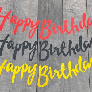 May include: Three separate Happy Birthday banners in cursive script. The top banner is red, the middle banner is black, and the bottom banner is yellow. Each banner features small circular holes at the top for hanging, displayed in a horizontal row.