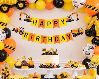 May include: A construction-themed party set featuring a Happy Birthday banner, yellow and orange balloons with black caution stripes, a cake topped with a toy dump truck, cupcakes with traffic cone toppers, and black and yellow striped napkins.