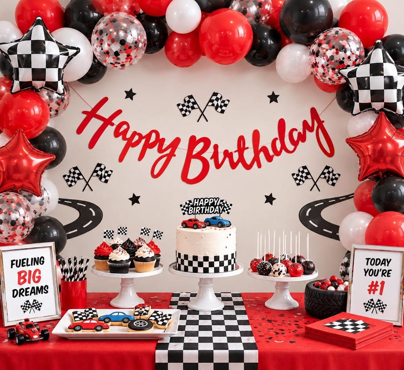 May include: A race car themed birthday party setup featuring a red, black, and white balloon arch, a cake with a checkered base, cupcakes with checkered flag toppers, and signs reading Happy Birthday, Fueling Big Dreams, and Today You're #1.