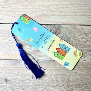 May include: A blue and yellow bookmark with a beach scene and the text "I'd rather be at the seaside". The bookmark has a blue tassel.