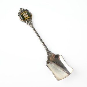 May include: Silver souvenir spoon with a green and gold enamel charm featuring the words "Mid Hants Railway".