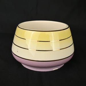 May include: A ceramic bowl with a gradient design in shades of yellow, white, and purple. The bowl has gold trim around the edges.