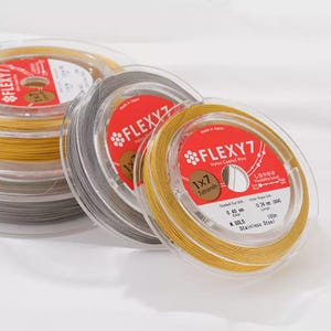 May include: Spools of Flexy7 nylon coated wire in gold and gray. Each spool is labeled with product information, including the wire's diameter, length, and material. The text on the label reads "Flexy7 Nylon Coated Wire" and "Stainless Steel".