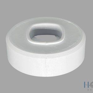 Puede incluir: Anillo de plástico blanco con un agujero cuadrado en el centro. El anillo tiene un diámetro de aproximadamente 5 cm.