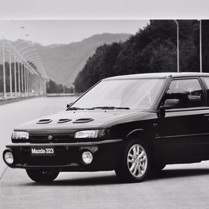 Grande foto Mazda 323 (macchina fotografica fotografia auto auto concessionaria di lusso concessionaria stampa poster auto motore giapponese berlina capella)