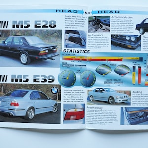 Puede incluir: Una doble página de revista que compara dos modelos BMW M5, el E28 y el E39. El E28 es negro y el E39 es plateado. La doble página incluye estadísticas de rendimiento, un veredicto y una comparación cara a cara de los dos coches.