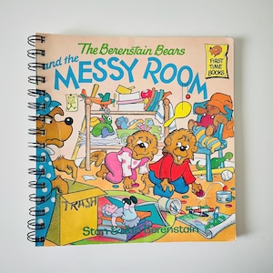 May include: A spiral-bound children's book titled "The Berenstain Bears and the Messy Room." The cover features an illustration of the Berenstain Bears in a messy room with toys and other items scattered around. The book is a "First Time Books" edition.
