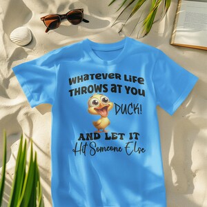 May include: A light blue t-shirt with a cartoon duck and the text "Whatever life throws at you duck! And let it hit someone else".