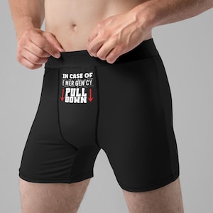 May include: Black boxer shorts with the text "IN CASE OF EMERGENCY PULL DOWN" and red arrows pointing down.
