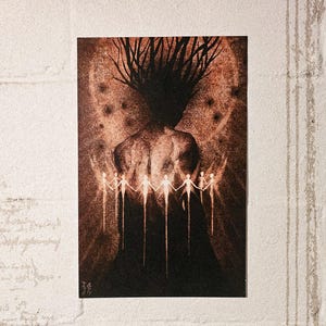 May include: A sepia-toned art print featuring a figure with a textured back and a crown of branches. Below, a circle of figures hold hands. The background has a speckled pattern, and the print is set against a white brick wall.