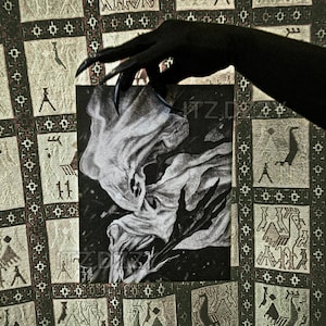 May include: A black and white illustration of a spectral figure with flowing fabric and clawed hands. The artwork is held by a black hand with long, sharp nails, set against a patterned background.