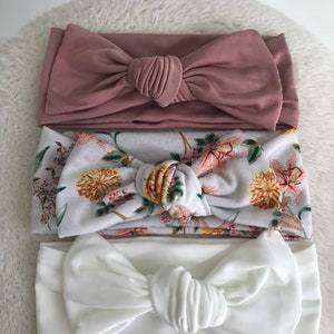 Pode incluir: Tr&ecirc;s faixas de cabe&ccedil;a com n&oacute; em diferentes cores e padr&otilde;es. A faixa de cabe&ccedil;a superior &eacute; de cor rosa p&oacute; s&oacute;lido. A faixa de cabe&ccedil;a do meio &eacute; branca com um padr&atilde;o floral. A faixa de cabe&ccedil;a inferior &eacute; de cor branca s&oacute;lida.