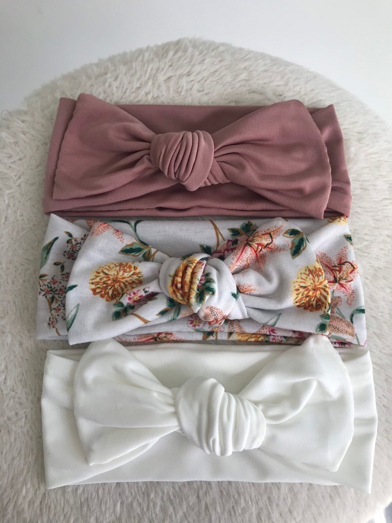 Pode incluir: Tr&ecirc;s faixas de cabe&ccedil;a com n&oacute; em diferentes cores e padr&otilde;es. A faixa de cabe&ccedil;a superior &eacute; de cor rosa p&oacute; s&oacute;lido. A faixa de cabe&ccedil;a do meio &eacute; branca com um padr&atilde;o floral. A faixa de cabe&ccedil;a inferior &eacute; de cor branca s&oacute;lida.