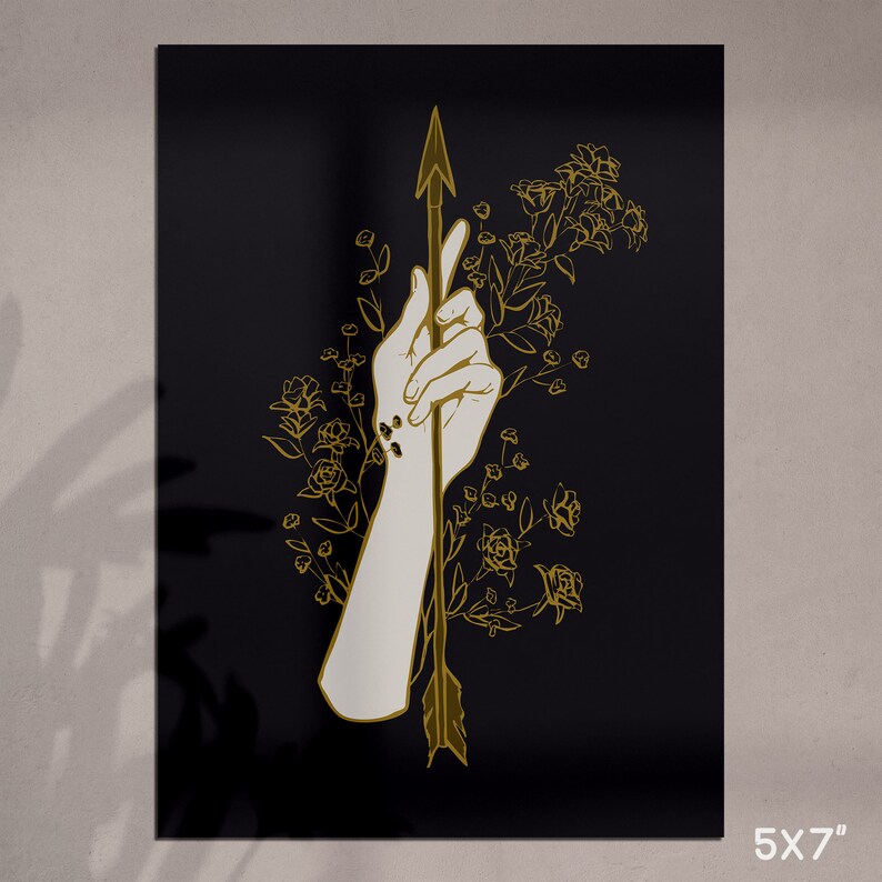 May include: A gold arrow piercing through a hand with a floral design on a black background. The arrow and flowers are outlined in gold.