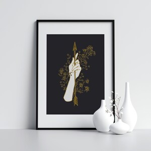 May include: A black and white illustration of a hand holding a gold arrow with floral details on a black background.