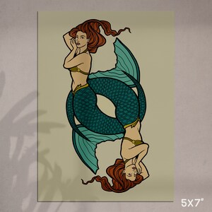 May include: A 5x7 inch print featuring two mermaids in a mirrored design. The mermaids have red hair, teal fishtails, and are wearing olive green tops. The background is a light beige color.