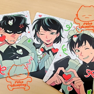 Könnte beinhalten: Drei illustrierte Karten mit Anime-Charakteren in Maid-Outfits. Jede Karte zeigt einen anderen Ausdruck und eine andere Pose, mit Herzen und dekorativen Elementen. Die Karten tragen den Text "robo dumpling" und ein katzenförmiges Logo.