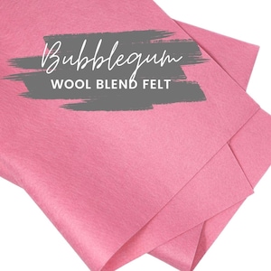 May include: A stack of bubblegum pink wool blend felt sheets. The text "Bubblegum" is written in cursive above "WOOL BLEND FELT" in a sans-serif font, all on a gray background.