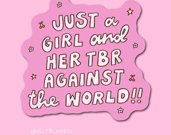 May include: A pink sticker with the text "JUST a GIRL and HER TBR AGAINST the WORLD!!" in a handwritten style. The sticker has a wavy outline and is decorated with small stars and cherries.