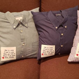 May include: Four decorative pillows made from button-down shirts in various colors and patterns, including blue, gray, and striped. Each pillow features a shirt collar and buttons, with a small patch of text that reads "This is a shirt I used to wear..." on the front.