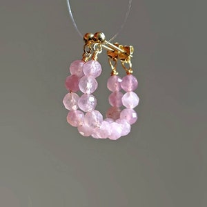 May include: A pair of pink gemstone hoop earrings with gold accents. The earrings are made with small, faceted beads.