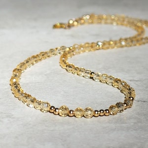 May include: A gold necklace with small, clear, faceted beads and gold spacers.