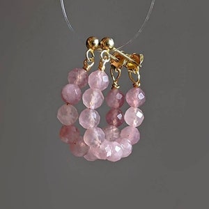 May include: A pair of pink and gold hoop earrings made with faceted rose quartz beads.