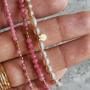 Puede incluir: Tres pulseras delicadas. Una est&aacute; ensartada con peque&ntilde;as cuentas rosas facetadas y detalles dorados. Otra presenta perlas rosas y cuentas doradas. La tercera pulsera est&aacute; hecha de perlas rosas y detalles dorados. Las pulseras se muestran sobre un fondo claro.
